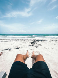 Low section of man on beach against sky