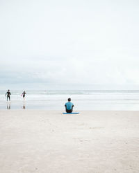 Rear view of men sitting on beach