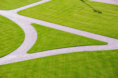 Cobbled park alleys and a wooden park bench. all surrounded by green grass on a sunny, spring day.