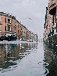 Canal amidst buildings in city during rainy season