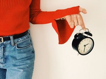 Close-up of hand holding clock against white background