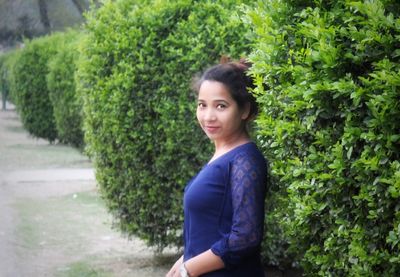 Portrait of young woman standing by plants