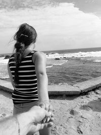 Woman sitting on beach looking at sea against sky