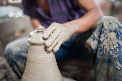 Midsection of woman making clay pot in workshop