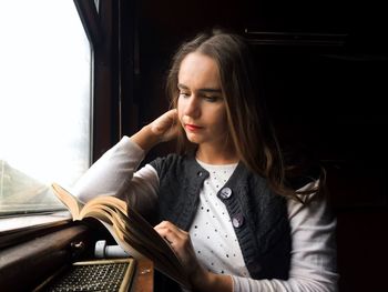 Close-up of young woman reading book while traveling in train