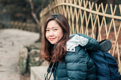 Portrait of smiling young woman sitting outdoors during winter