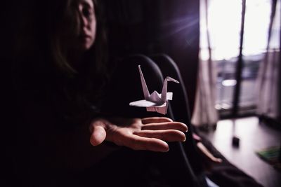 Bird origami levitating over hand of woman at home