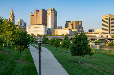 Trees and buildings in city against clear sky