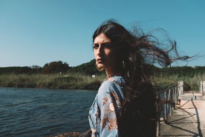 Portrait of woman at lakeshore against clear sky