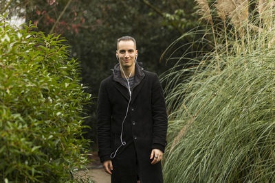 Portrait of young man standing against plants