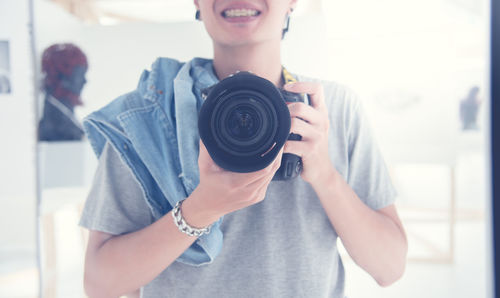 Midsection of woman holding dslr camera