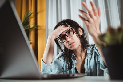 Low angle view of woman with head in hand working over laptop at home