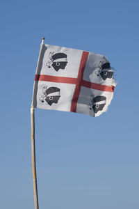 Low angle view of flag against clear blue sky