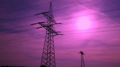 Low angle view of electricity pylon against cloudy sky