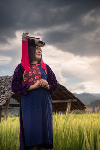 Young woman standing on field against sky