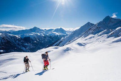 People skiing on snowcapped mountains against sky