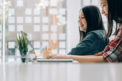 Young woman using phone while sitting on table