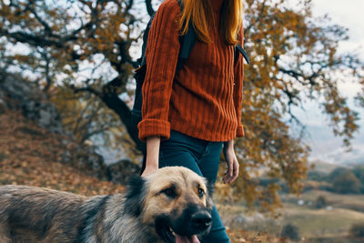 Rear view of woman with dog against trees during winter