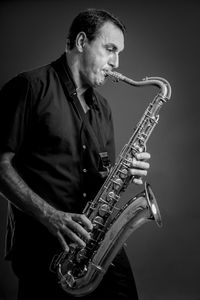 Mature man playing saxophone against wall