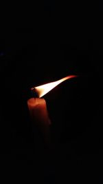 Close-up of lit candle in darkroom