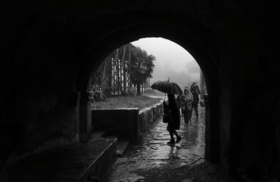 People on wet street seen through tunnel