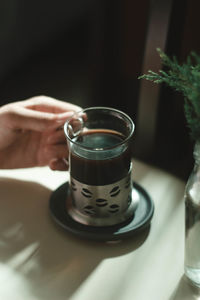 Close-up of hand holding drink on table