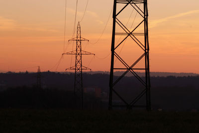 Silhouette electricity pylon on field against sky during sunset