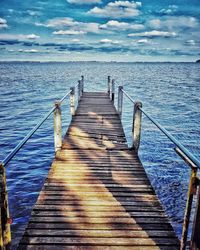 Wooden pier over sea against sky