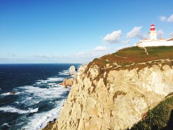 Lighthouse by sea against sky