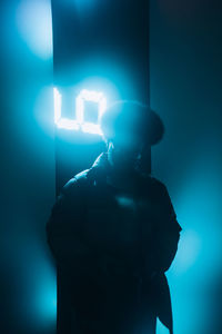 Man standing against illuminated wall