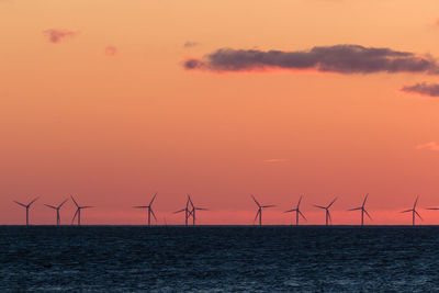 Wind turbines in sea at sunset