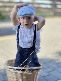 Boy wearing beret standing in wicker basket wearing shorts with suspenders dynamism emotion retro 