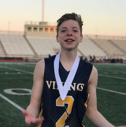 Portrait of young boy with winning medal on football field 