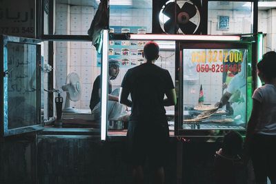 Rear view of people standing in glass window