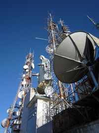 Low angle view of communications tower against blue sky