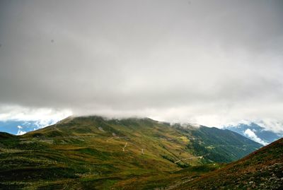 Scenic view of grassy landscape against cloudy sky