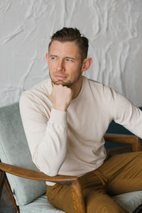 Handsome young man sitting in armchair indoors person