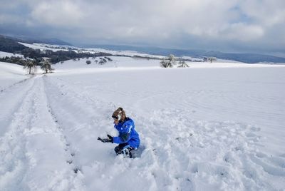 A boy  skiing on snowcapped field against sky