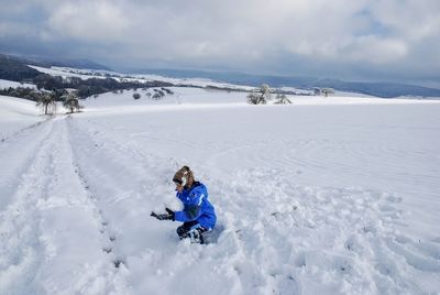 Man skiing on snowcapped field against sky