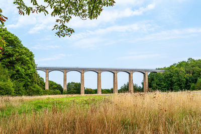 Arch bridge on field against sky