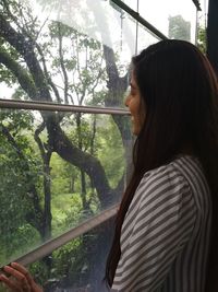 Side view of woman looking through window