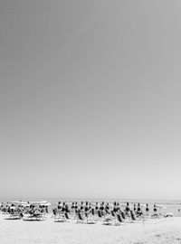 Group of people on beach against clear sky