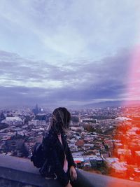 Rear view of woman looking at city buildings against sky