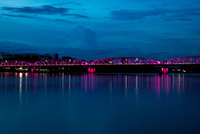 Illuminated bridge over river against sky at night