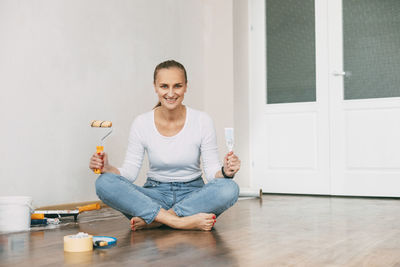 Woman in white clothes painting the walls in her large and bright room.