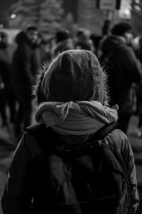 Rear view of person carrying backpack during protest at night