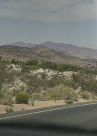 Road by mountains against sky