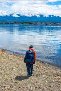 Rear view of man standing in lake against sky