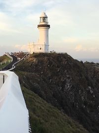 Lighthouse by building against sky