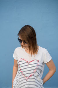 Beautiful woman standing against blue wall